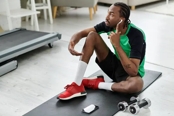 A young african american man engages in a workout while using technology in his home gym. — Stock Photo