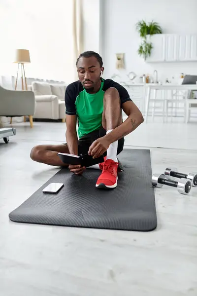 Un giovane afroamericano lavora a distanza su un tappetino da yoga, bilanciando fitness e produttività. — Foto stock