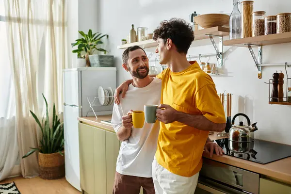 A loving gay couple shares warm drinks and laughter in their stylish kitchen. — Stock Photo