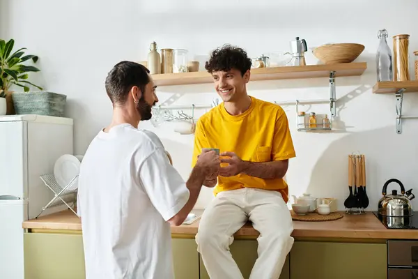 Deux hommes partagent un beau moment autour d'un café dans leur appartement élégant, embrassant l'amour et la joie. — Photo de stock