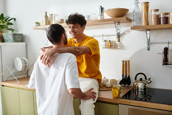 Two men in casual attire embrace playfully in their stylish home kitchen. — Stock Photo