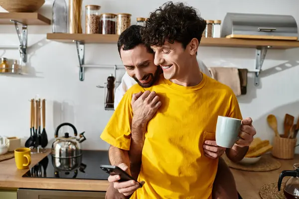 Two men embrace lovingly while enjoying a relaxed moment in their modern kitchen. — Stock Photo
