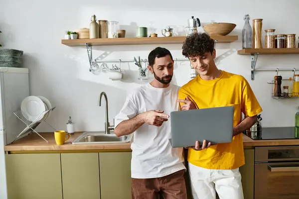 Couple enjoys each others company while working on a laptop in their stylish kitchen. — Stock Photo