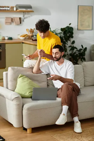 Two men share a loving moment while engaging with their devices in a stylish home. — Stock Photo
