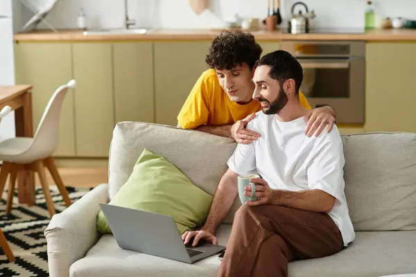Two men share a joyful moment while using a laptop in their cozy living space. — Stock Photo