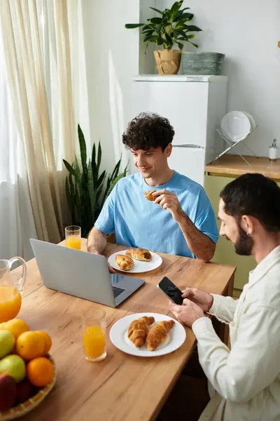 Two men share a delightful breakfast, enjoying pastries and drinks in their modern home. — Stock Photo