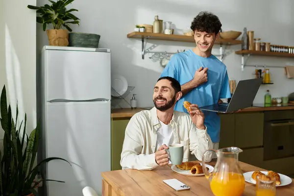 Dois homens compartilham alegremente um café da manhã em seu elegante apartamento, saboreando comida e momentos matinais.. — Fotografia de Stock