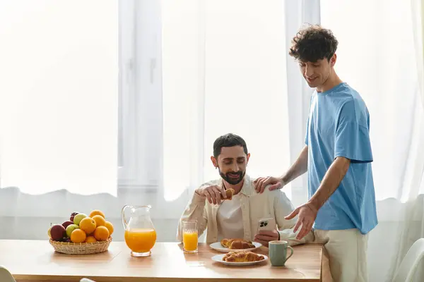 Una coppia gay condivide un'accogliente colazione, assaporando cibo e amore nel loro appartamento moderno. — Foto stock