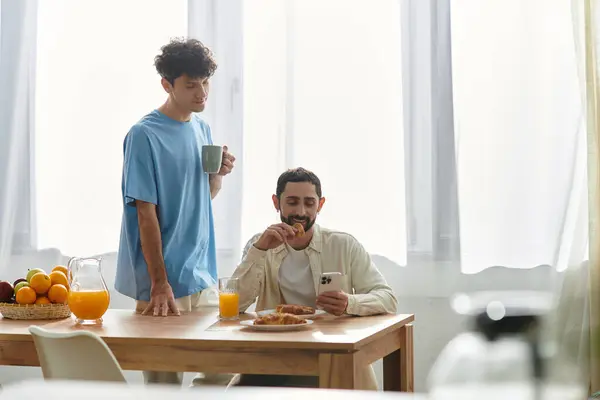 A gay couple in casual attire savoring a delicious breakfast together in their modern apartment. — Stock Photo