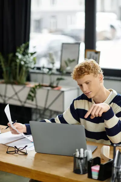 In a contemporary office space, a young redhead man analyzes information while working. — Stock Photo