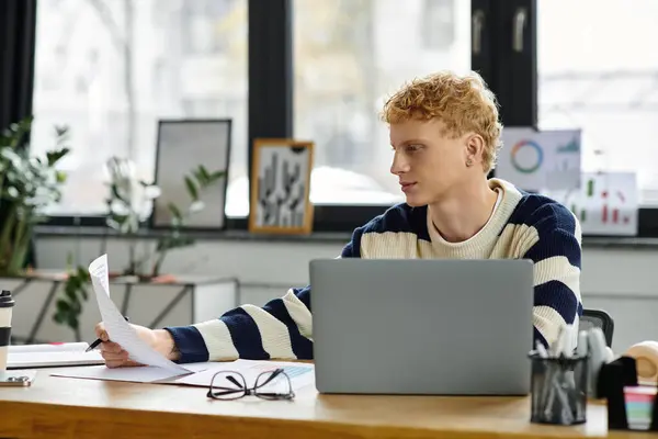 Focused young man analyzes reports at his desk in a contemporary office setting. — Stock Photo