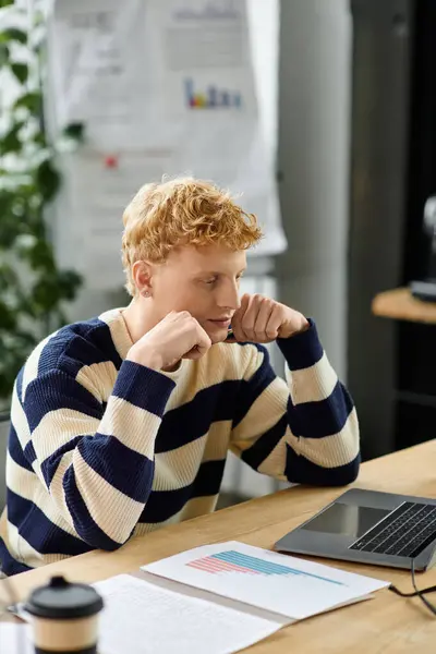 Young professional intently reviews details on a laptop in a contemporary office setup. — Stock Photo