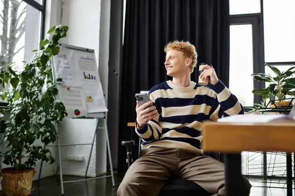 Joven profesional sonríe mientras usa su teléfono inteligente en una oficina brillante y contemporánea. - foto de stock