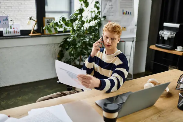 Redhead manager reviews documents while on a phone call in a contemporary workspace. — Stock Photo