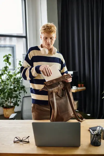 A young redhead man organizes his materials in a corporate office environment. — Stock Photo