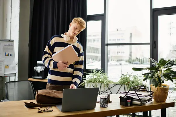 Jeune homme rousse en pull rayé travaille avec diligence à un bureau élégant. — Photo de stock