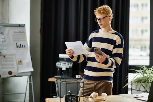 Young professional analyzes paperwork while balancing a smartphone in a stylish office. — Stock Photo