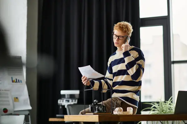 A young redhead professional engages in work while seated at a desk in a corporate office. — Stock Photo