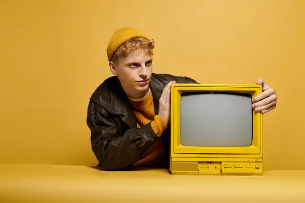 Young man with red hair showcases a stylish winter outfit leaning on a retro TV — Stock Photo