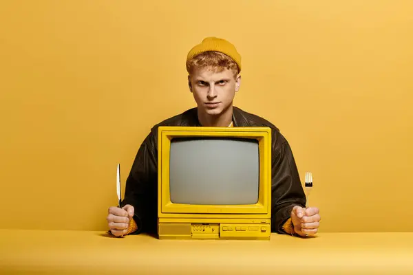 Uma jovem ruiva da moda exibe um olhar ousado de inverno com uma televisão vintage contra um cenário amarelo vibrante. — Fotografia de Stock