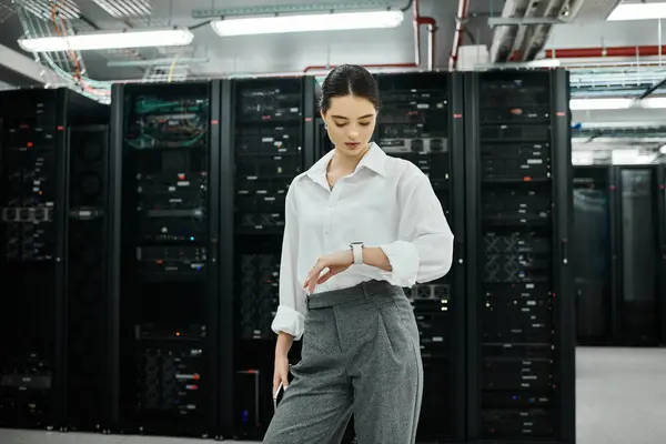 Una donna concentrata in camicia bianca gestisce i sistemi server in un data center all'avanguardia. — Foto stock