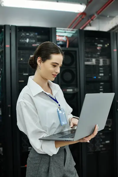 Specialista IT in camicia bianca si impegna con un computer portatile tra hardware server in un data center. — Foto stock