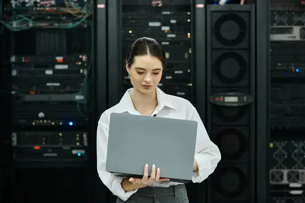 Ein IT-Spezialist im weißen Hemd arbeitet an einem Laptop inmitten von Serverschränken in einem Rechenzentrum. — Stockfoto