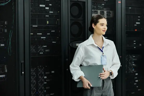 Una donna sicura di sé in camicia bianca gestisce le attività IT in una sala server high-tech. — Foto stock