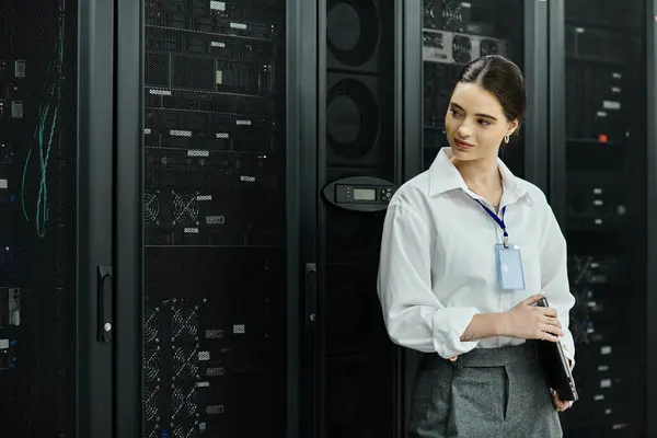 Una donna professionista in camicia bianca monitora i sistemi server in una moderna struttura tecnologica. — Foto stock
