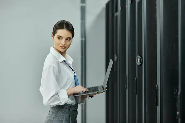 Una donna in camicia bianca gestisce abilmente i compiti in una moderna sala server piena di hardware. — Foto stock