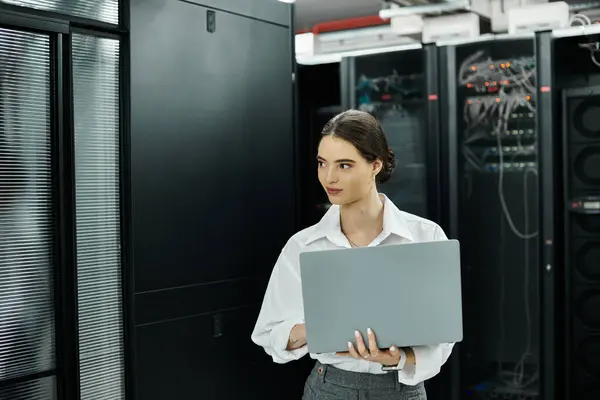 Eine professionelle Frau im weißen Hemd arbeitet an ihrem Laptop im Serverraum für die Sicherheit. — Stockfoto