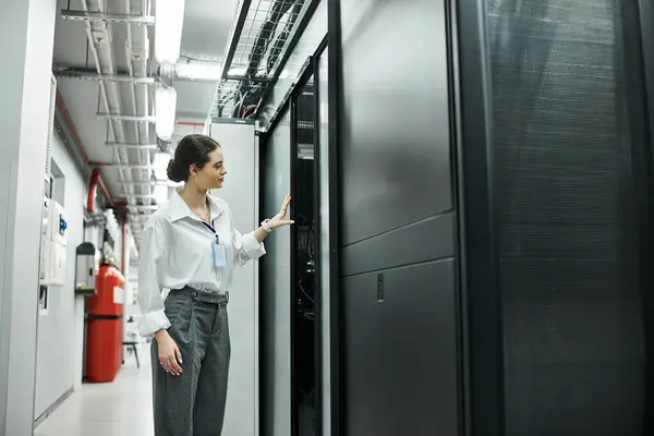 Una donna esperta in camicia bianca ispeziona hardware e sistemi del server nel data center. — Foto stock