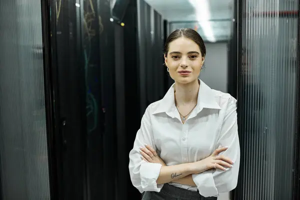 Una donna con una camicia bianca supervisiona le operazioni del server in un elegante data center garantendo al contempo la sicurezza. — Foto stock