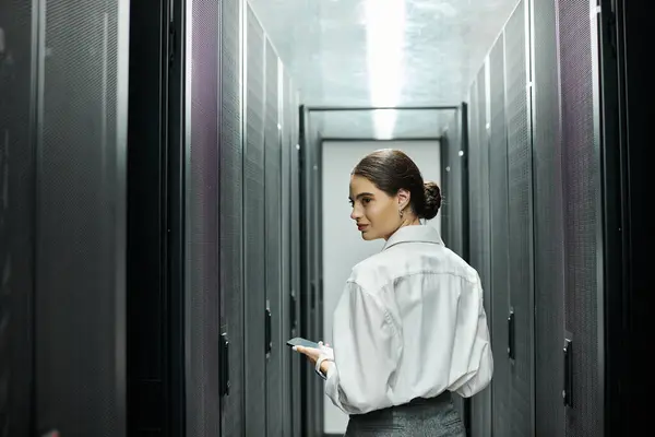 Una donna esperta in camicia bianca naviga in una sala server contemporanea, garantendo l'integrità del sistema. — Foto stock