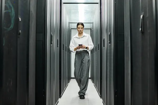 Eine Frau im weißen Hemd navigiert durch den Serverraum und sorgt dafür, dass die Systeme reibungslos laufen. — Stockfoto