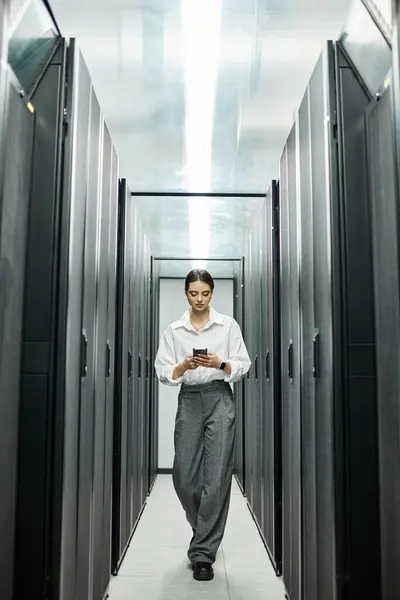 Una donna professionista in camicia bianca lavora con un dispositivo mobile in un data center. — Foto stock