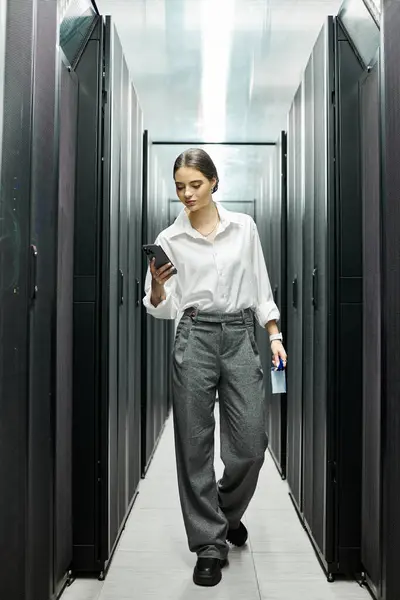 Una donna in camicia bianca naviga in una sala server, monitorando i sistemi e garantendo la sicurezza. — Foto stock