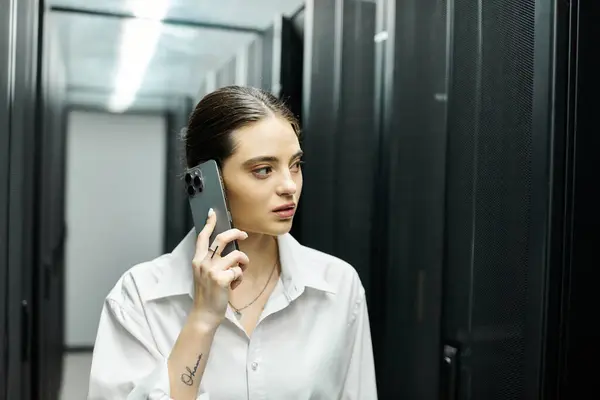 Женщина в белой рубашке общается по телефону, управляя серверными системами в технологической среде. — стоковое фото