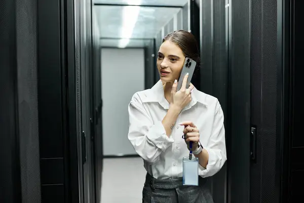 A skilled IT specialist in a white shirt engages on a phone call in the data center. — Stock Photo