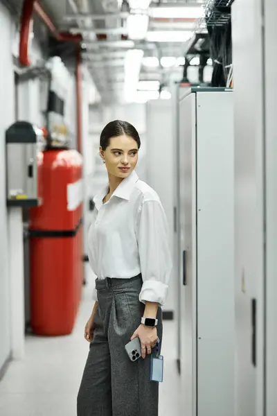 Una donna in camicia bianca lavora diligentemente in una sala server high-tech, supervisionando i sistemi. — Foto stock