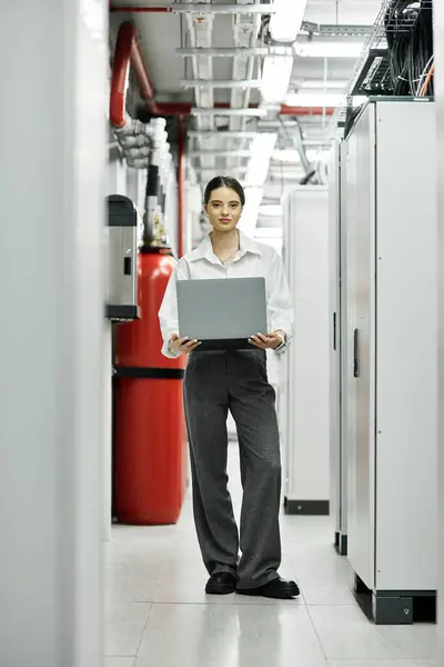 Eine professionelle Frau im weißen Hemd bedient einen Laptop in einem High-Tech-Serverraum. — Stockfoto
