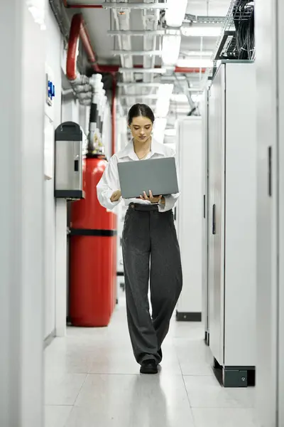 Uno specialista IT manovra una sala server con un computer portatile, mantenendo i sistemi in funzione senza intoppi. — Foto stock