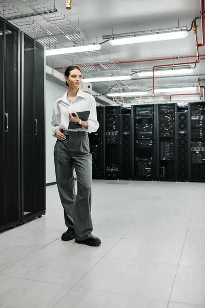 Una donna professionista in camicia bianca si trova con fiducia in una sala server high-tech. — Foto stock