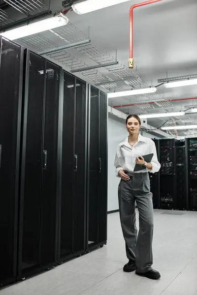 Una donna esperta in camicia bianca controlla i sistemi mentre gestisce l'hardware del server in un hub tecnologico. — Foto stock