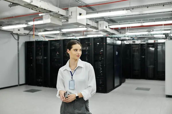 Eine Frau im weißen Hemd überwacht den Betrieb in einem geschäftigen Serverraum und sorgt für digitale Sicherheit. — Stockfoto