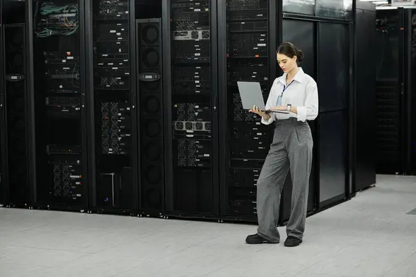 Una donna in camicia bianca e pantaloni grigi gestisce l'hardware del server in un data center. — Foto stock