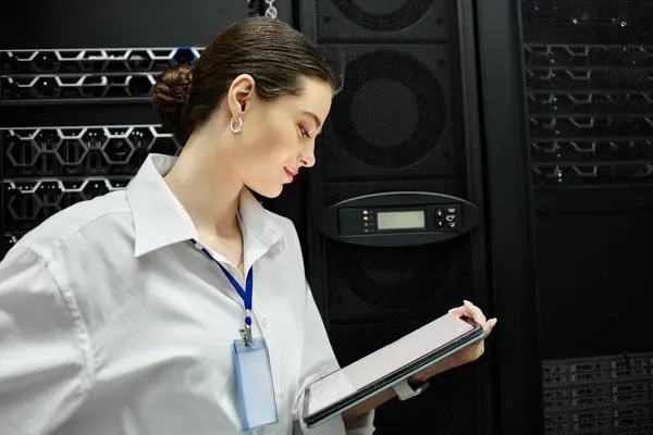 In a sleek server room, a woman in a white shirt inspects devices and manages systems. — Stock Photo