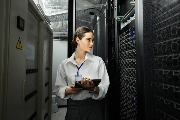Una donna esperta in camicia bianca supervisiona le operazioni del server e la sicurezza dei dati in tecnologia. — Foto stock