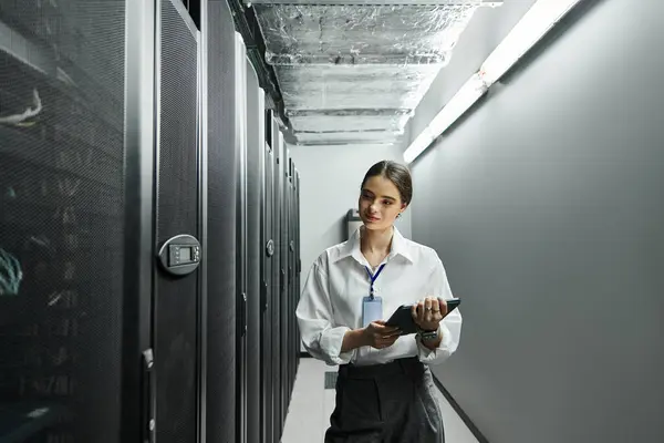 Une femme en chemise blanche travaille avec diligence dans une salle de serveurs élégante, gérant les systèmes. — Photo de stock