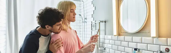 Los hombres comparten un momento íntimo mientras se preparan juntos en un baño luminoso. - foto de stock